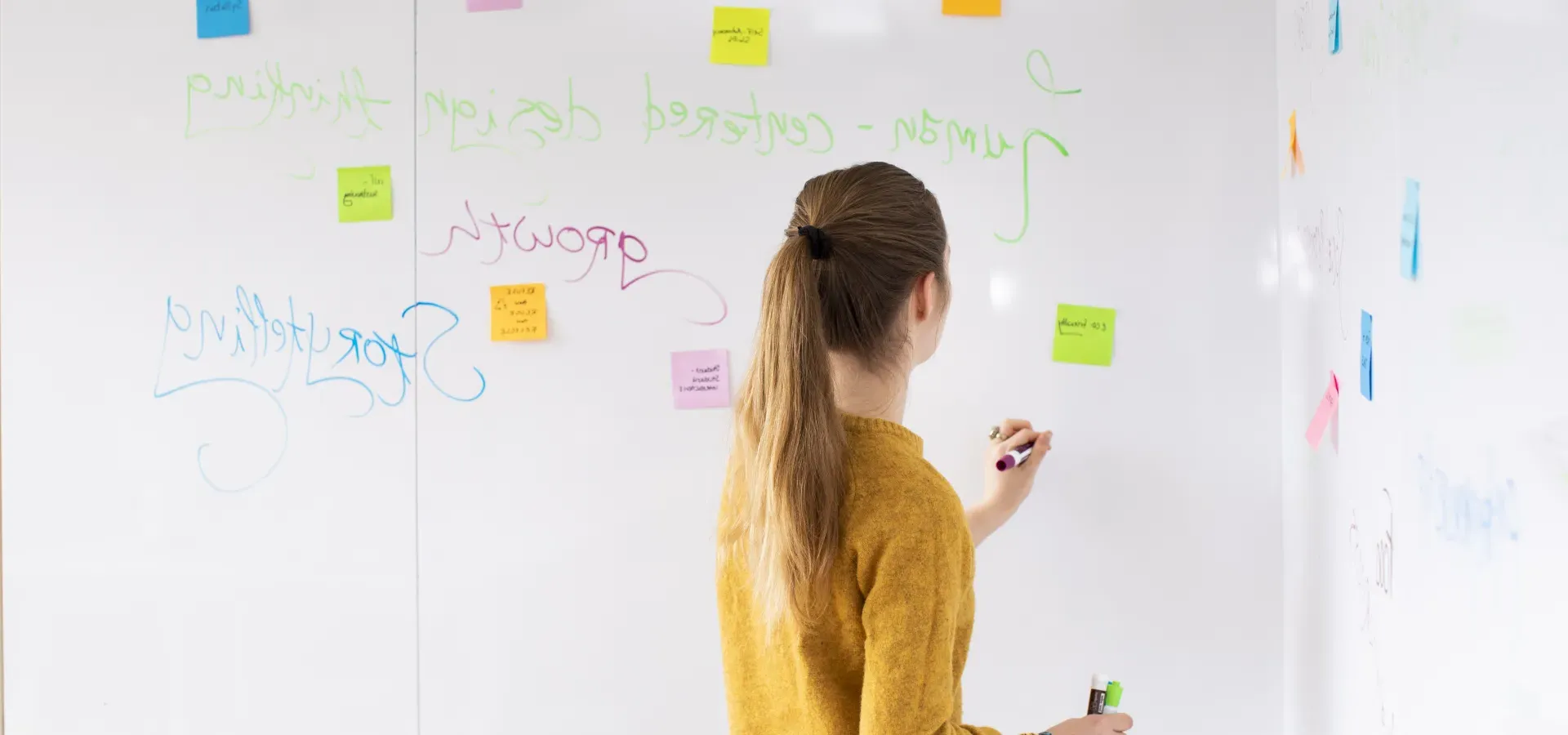 A student stands at a white board, writing.